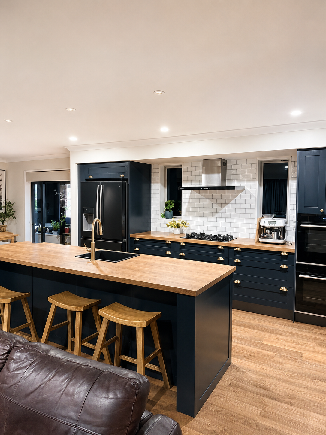 Completed modern farmhouse kitchen with timber benchtops, dark cabinetry and brass handles